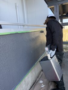 大垣市アパート外壁塗装 仕上げ塗装中|職人がローラーでグレー系アクセントカラーを塗り重ねている様子